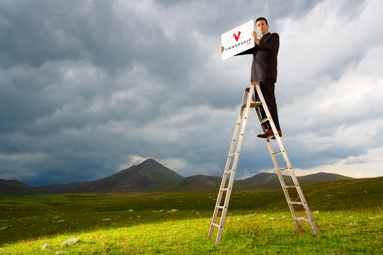 Make money on YouTube — man standing on ladder with sign
